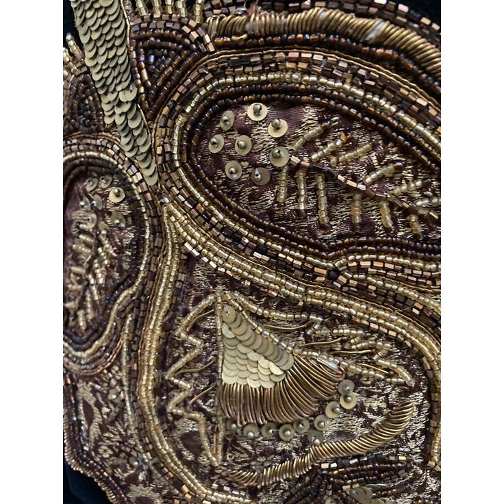 an intricately designed piece of fabric with gold and brown beads