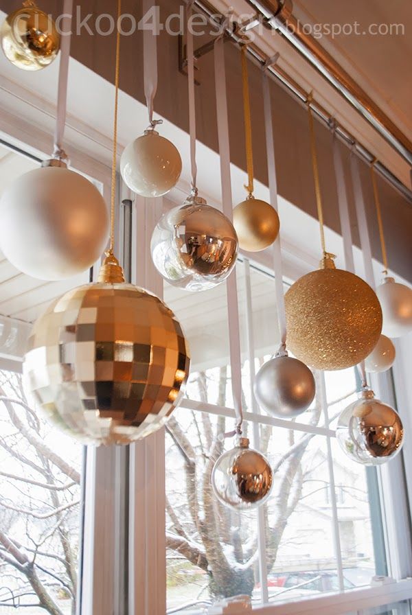 several ornaments hanging from a window in front of a tree