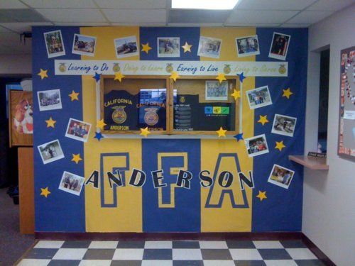 an office cubicle decorated with yellow and blue stripes, stars and photos on the wall