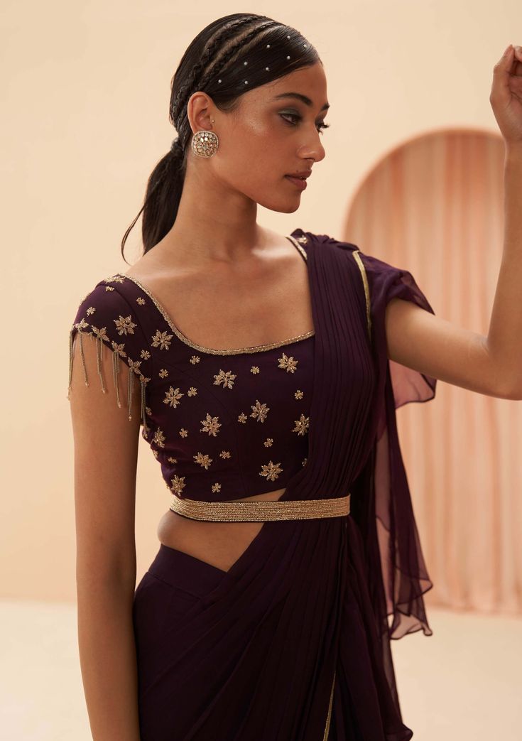 Editors Note Step into the spotlight with this ruffle dramatic sari ensemble. The sari is adorned with intricate embroidery, while the blouse features a chic chain detail on the sleeves. It's a perfect choice for those who want to make a bold and stylish statement at any event. Wine Saree, Indian Wedding Bride, Draped Saree, Add Sleeves, Indian Bridal Lehenga, Party Sarees, Drape Saree, Blouse Saree, Embroidery Floral