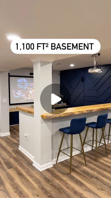 an image of a basement bar with stools in the foreground and a projector screen on the wall behind it