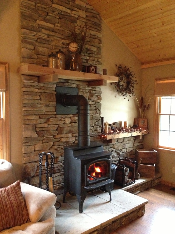 a living room with a fire place in the corner and stone walls on both sides