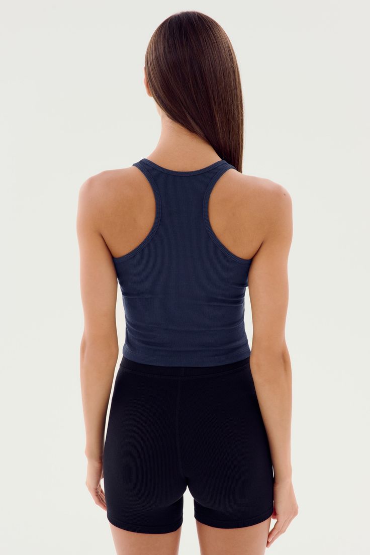 the back of a woman wearing black shorts and a tank top with an open neck