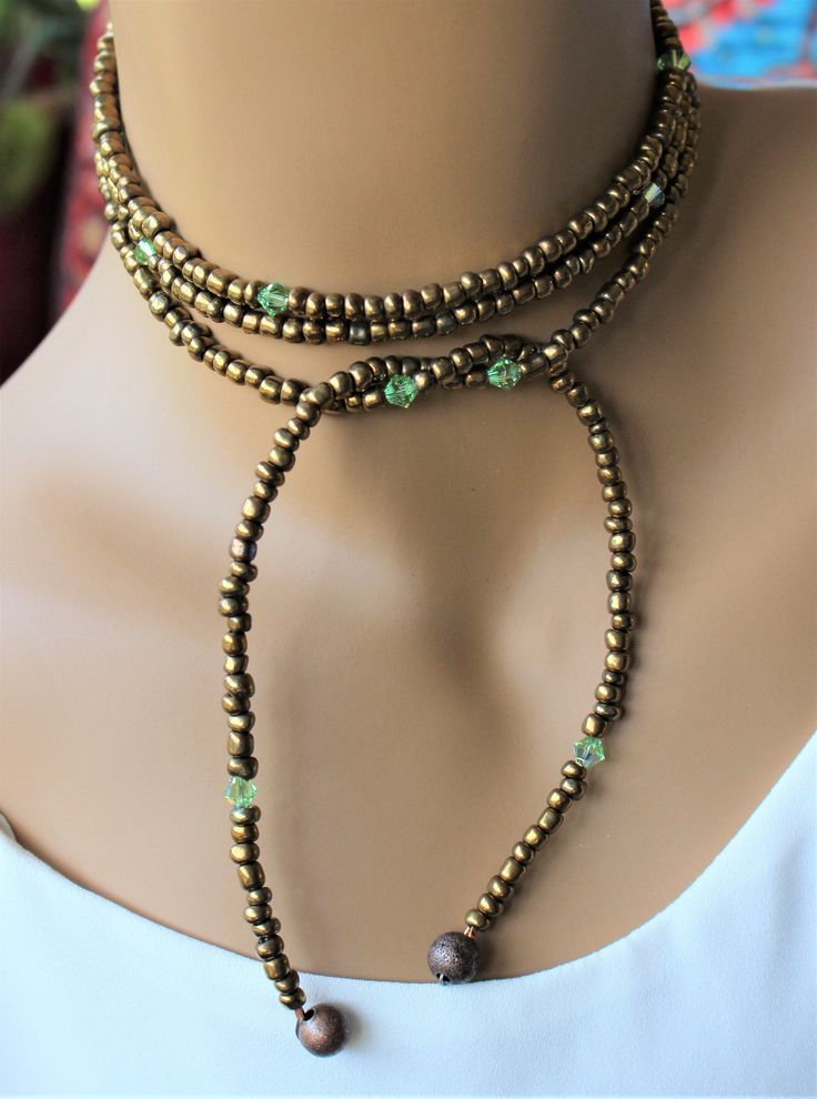 This beautiful lariat is comprised of bronze seed beads with peridot glass accents. Adjustable Tiny Beads Lariat Necklace, Adjustable Lariat Necklace With Tiny Beads, Adjustable Green Beaded Lariat Necklace, Adjustable Beaded Lariat Necklace For Festivals, Artisan Adjustable Jewelry With Gold Beads, Traditional Beaded Lariat Jewelry, Artisan Jewelry With Adjustable Gold Beads, Artisan Adjustable Gold Beads Jewelry, Adjustable Lariat Hand-strung Beads