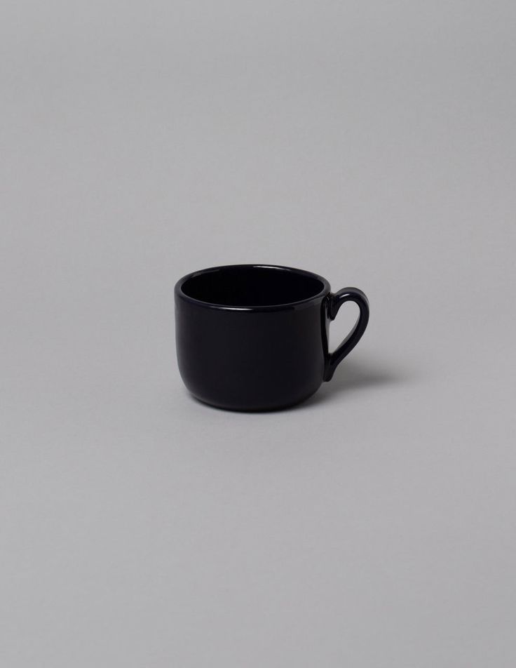 a black coffee cup sitting on top of a table