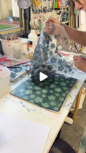 a woman is working on an art project in her studio with paper and glues