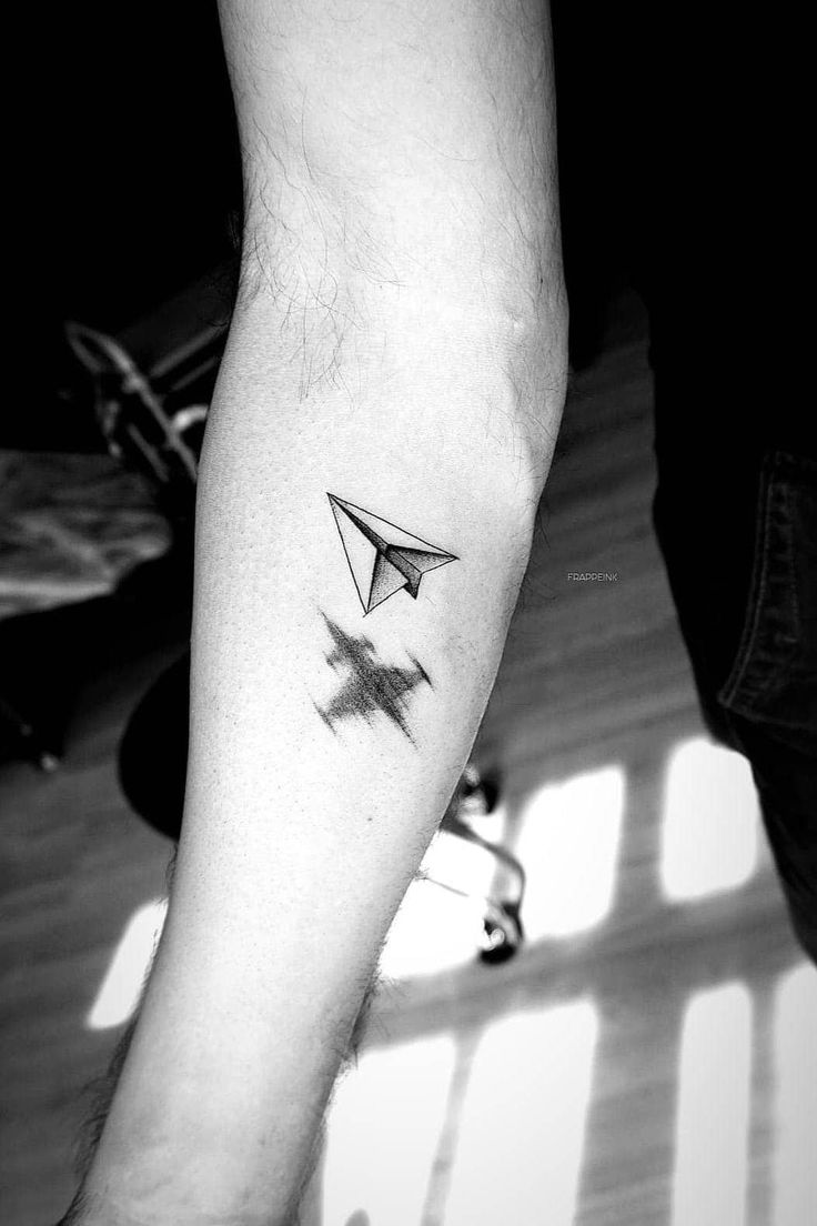 a person with a small tattoo on their arm that has a paper airplane in it