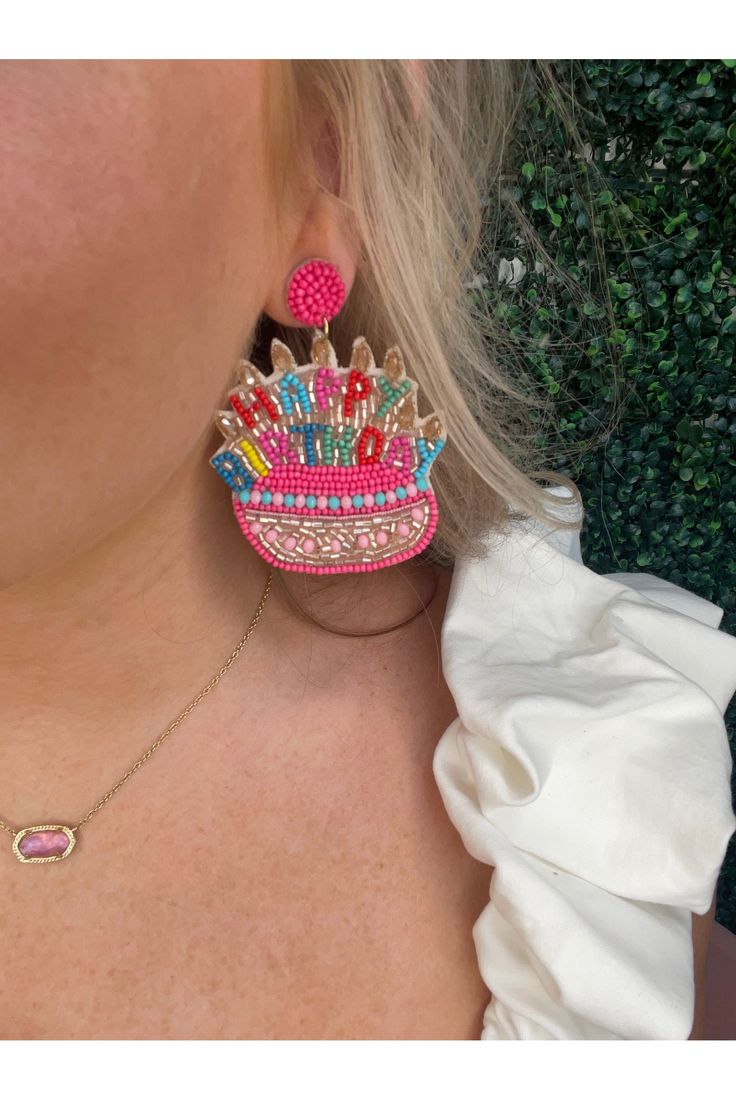 a close up of a woman's face wearing large earrings with colorful designs on them