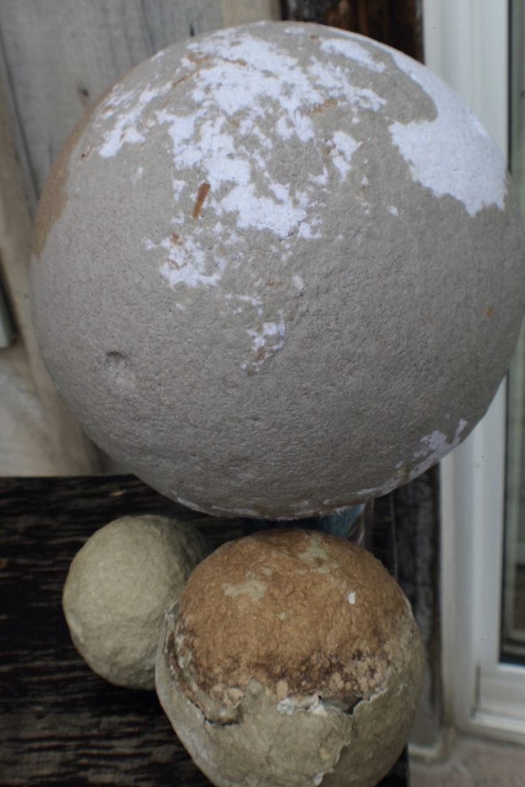 three balls stacked on top of each other in front of a wooden fence and window