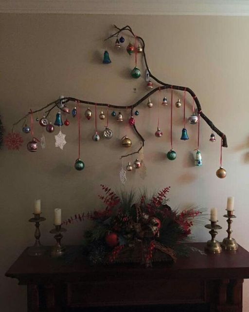 a christmas tree with ornaments hanging from it's branches in front of a fireplace