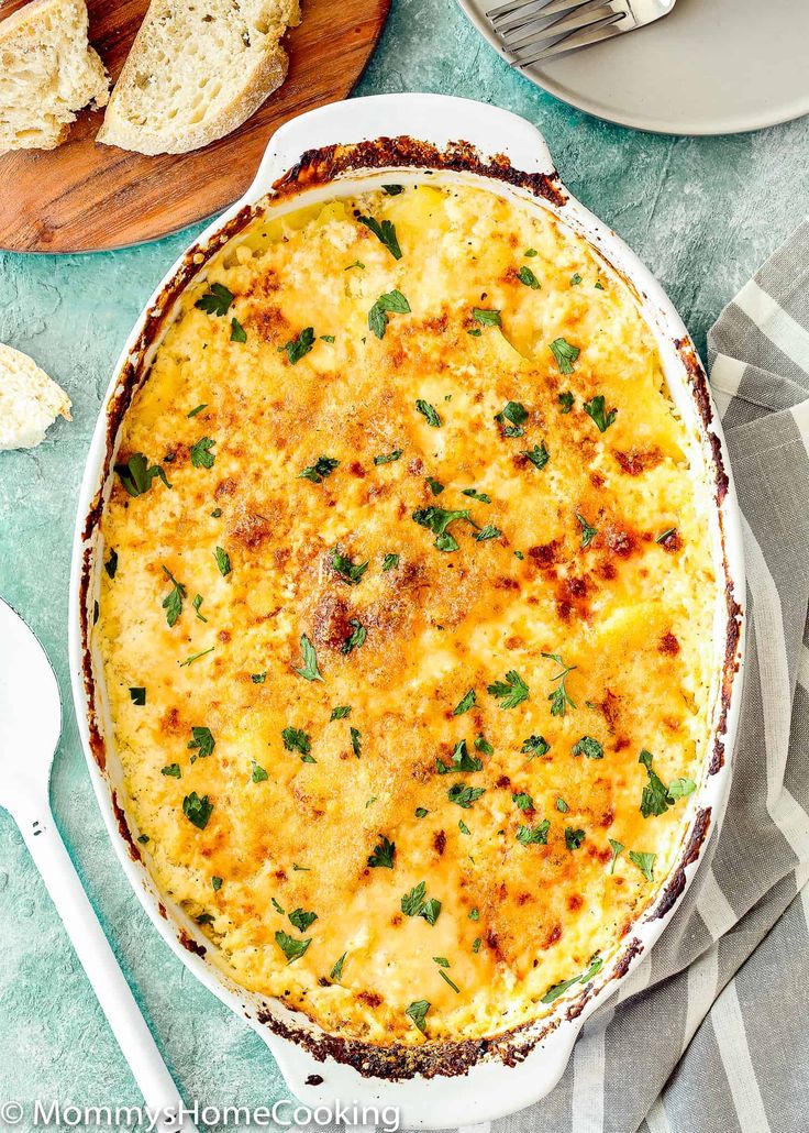 an egg casserole in a white dish on a table with bread and butter