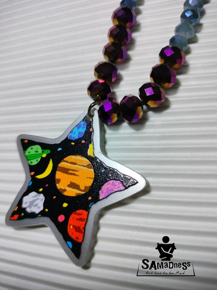 The Starlight Voyager necklaces capture the awe-inspiring beauty of the cosmos. A clear plexiglass star pendant displays a mesmerizing space scene, acting as a window to distant galaxies. The pendant hangs from a sleek black cord, accented with vibrant shimmering purple gold-toned,blue beige and cool light blue beads, adding a touch of celestial elegance. Whether you're a space enthusiast or simply drawn to unique, eye-catching jewelry, those necklaces is sure to spark your imagination and draw Space-themed Star Jewelry For Gifts, Space-themed Star Jewelry For Gift, Space-themed Star Jewelry Gift, Space-themed Star Shaped Jewelry Gift, Star-shaped Resin Jewelry For Gifts, Star Shaped Resin Jewelry Gift, Unique Star-shaped Gift Necklace, Unique Star-shaped Necklace For Gift, Space Enthusiast