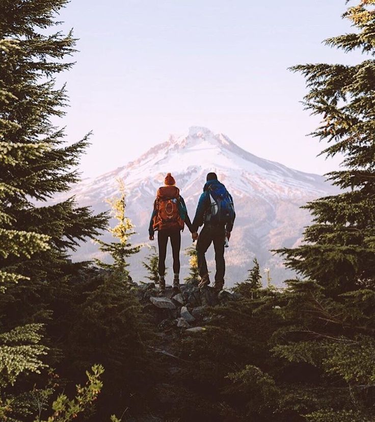 two people standing on top of a mountain holding hands