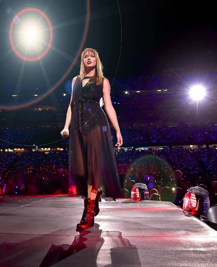 a woman standing on top of a stage in front of an audience at a concert