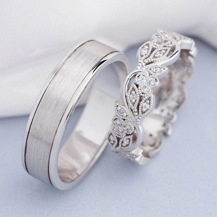 two wedding bands with diamonds on each side, one is white gold and the other is silver