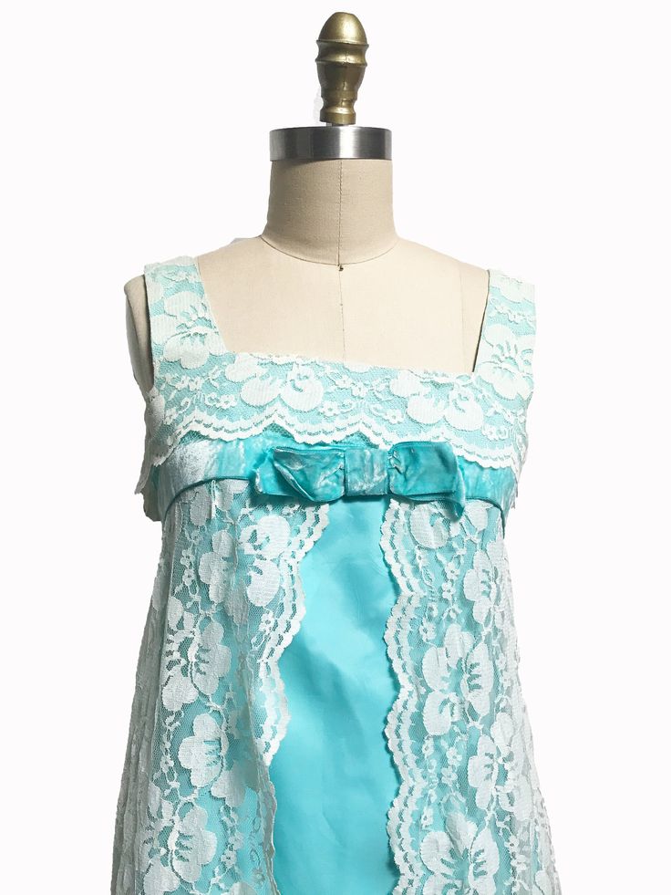 "This 1960's dress reminds me of a dress version of Marvelous Mrs. Maisel nightgown. It has a bright blue A-line shape dress with a overlay of lace that is not attached to the dress so when you walk it really moves with you. It has the original metal zipper up the back with a beautiful tule netting petite coat underneath. I tacked down the bow so it will no long flap as it shows in the picture. This dress would look great with white shoes and a high neck rhinestone necklace! Measurements: Fits l Sleeveless Blue Coquette Dress, Flirty Sleeveless Blue Dress, Summer Party Coquette Nightgown, Vintage Blue Wedding Nightgown, Coquette Summer Party Nightgown, Blue Vintage Wedding Nightgown, Blue Lace Trim Coquette Dress, Vintage Fitted Nightgown For Party, Coquette Sleeveless Nightgown For Party