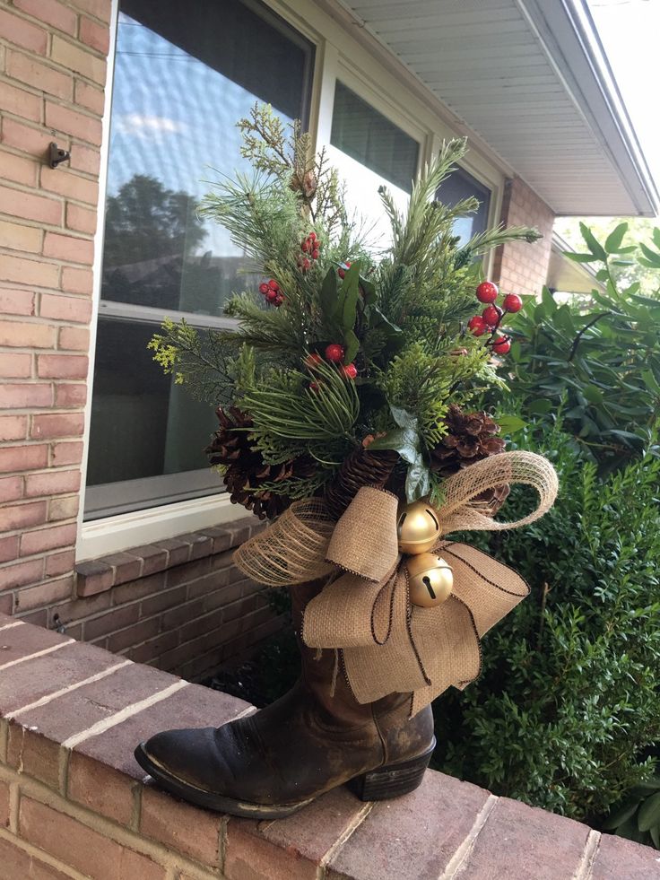 a boot is decorated with evergreen, berries and bells for the holiday door hanger