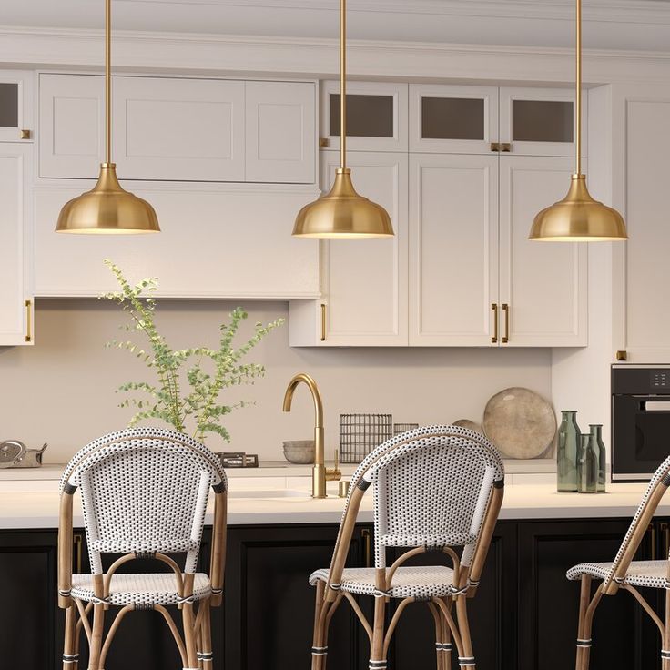 three wicker bar stools sit in front of a kitchen island with gold pendant lights