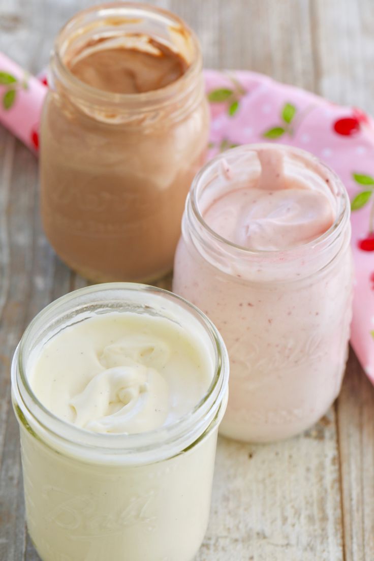 three jars filled with different types of food on top of a wooden table next to a pink towel