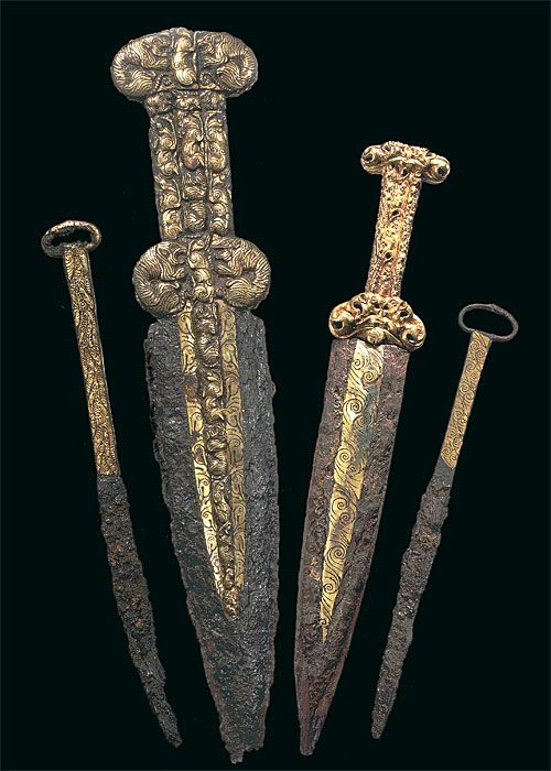 four ancient swords are shown in this image, one is gold and the other is silver