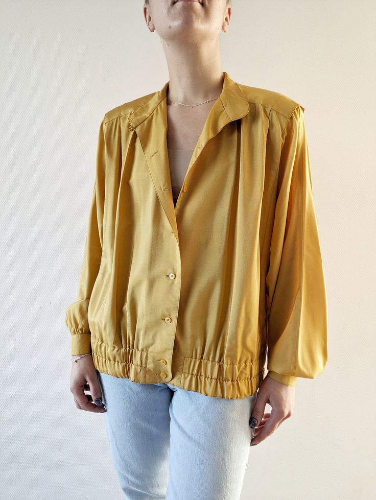 Beautiful 80's pure silk mustard yellow bomber blouson with batwing sleeves, Aries shoulder line (with shoulder pads), pleated front and side pockets. Fabric: 100% silk Size: 44, will fit size M (oversized fit) up to XL Measurement, single flat lying: Shoulders 45 cm Chest 60 cm Length 64 cm Sleeve 64cm Retro Relaxed Fit Blouse For Fall, Retro Solid Tops For Fall, Solid Retro Tops For Fall, Mustard Long Sleeve Blouse For Fall, Vintage Tops With Blouson Sleeves For Spring, Retro Mustard Long Sleeve Tops, Spring Vintage Tops With Blouson Sleeves, Mustard Retro Long Sleeve Tops, Mustard Long Sleeve Retro Top