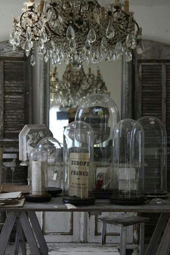 an old table with wine bottles and chandelier in the middle, surrounded by other items