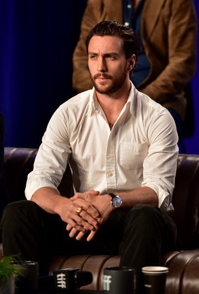 a man sitting on top of a brown couch next to another man in a white shirt