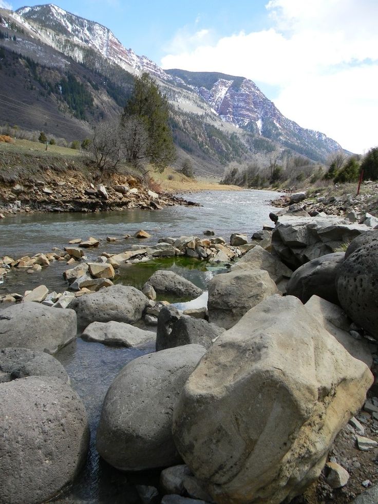 some rocks and water in the middle of a mountain stream with mountains in the background