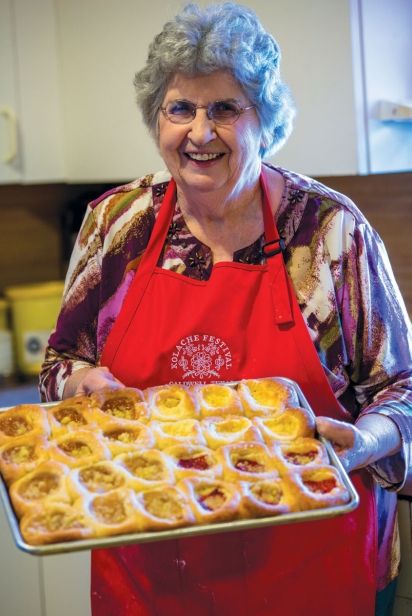 an older woman is holding a tray of food