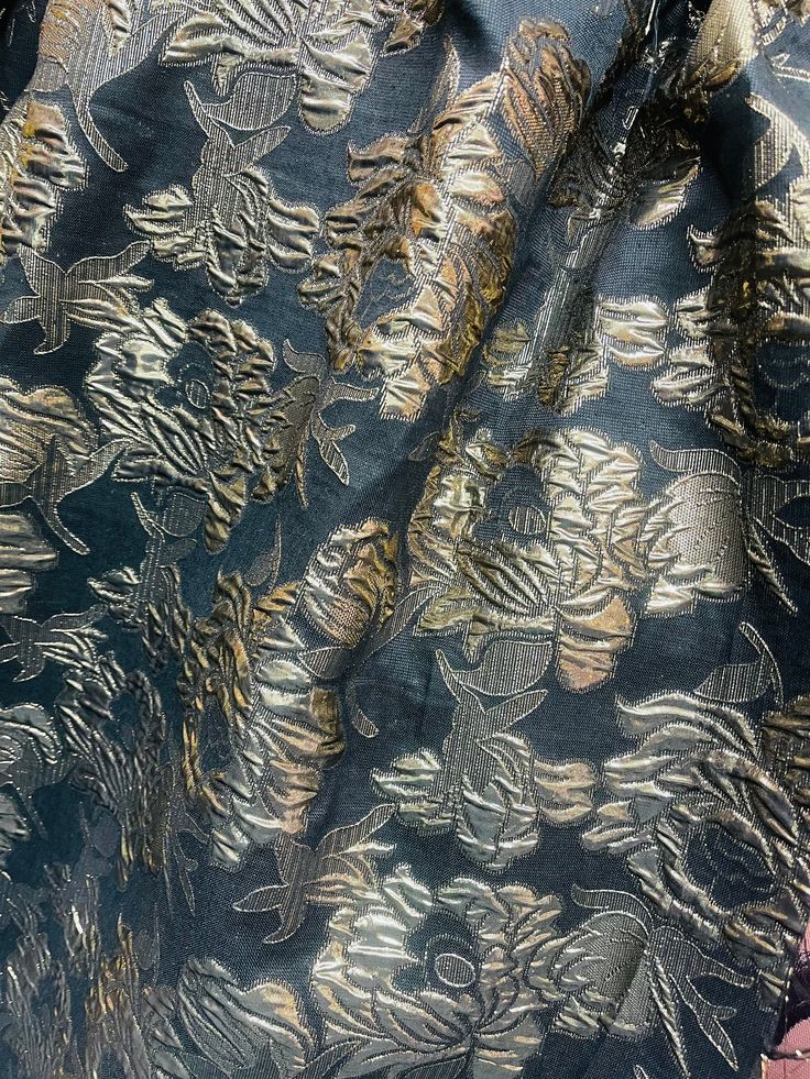 an image of a black and gold cloth with flowers on it, close up view