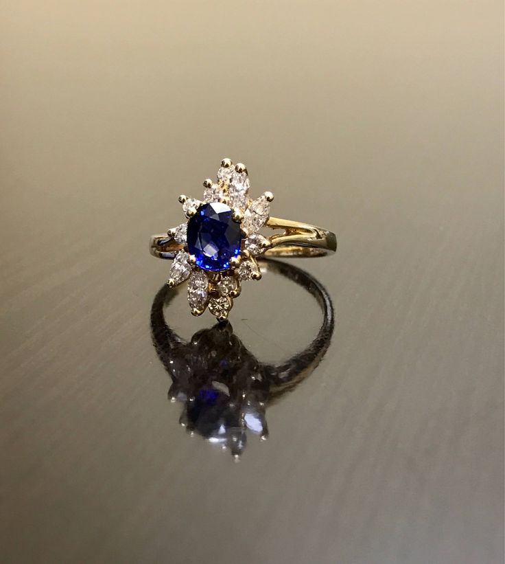 DeKara Designs Clearance Metal- 14K Yellow Gold, .583. Stones- 1 Oval Ceylon Blue Sapphire 0.80 Carats, 4 Marquise Diamonds G Color VS1 Clarity 0.40 Carats, 8 Round Diamonds H Color VS1 Clarity 0.20 Carats. Size- Ring is a 6 3/4, and could be sized up or down at no additional cost! FREE SIZING Handmade 14K Yellow Gold Ceylon Blue Sapphire Halo Diamond Ring. This ring is inspired by the Art Deco era with an enticing fiery oval shaped Ceylon Blue Sapphire. The sapphire is set in between 4 prongs. Blue 14k Gold Ring Stamped 14k, Blue Sapphire Ring In 14k Gold For Anniversary, Blue 14k Stamped Promise Ring, Blue Diamond Cluster Ring For Formal Occasions, Anniversary Blue Sapphire Ring In 14k Gold, Blue Sapphire Ring Stamped 14k For Gift, Blue 14k Gold Cluster Ring, Blue 14k Gold Cluster Ring Gift, Luxury Blue Marquise Cut Ring