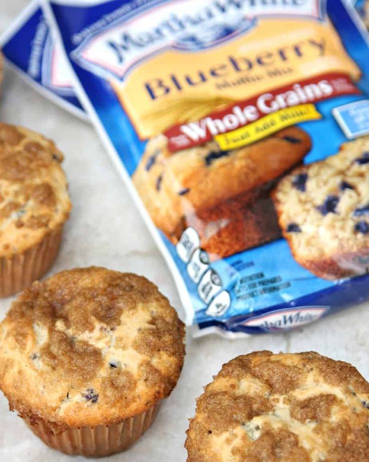 three blueberry muffins next to a bag of blueberries