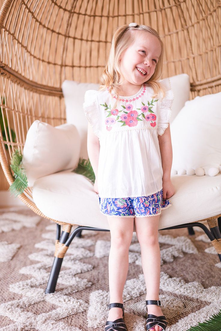 Introducing our newest blouse and short set! This adorable two-piece features a beautiful floral embroidered cotton blouse, paired with colorful block print shorts with little lace trim. She'll look absolutely precious in this ensemble - perfect for a day of play! Summer Cotton Sets With Floral Embroidery, Floral Embroidery Cotton Set For Summer, Floral Embroidered Cotton Summer Sets, Cotton Beach Sets With Floral Embroidery, Summer Floral Embroidery Cotton Sets, Beach Sets With Floral Embroidery In Cotton, Playful White Floral Print Sets, White Floral Embroidery Sets For Vacation, Cute Spring Sets For Day Out