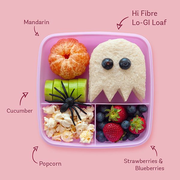 a pink plate topped with fruit and veggies next to a white monster face