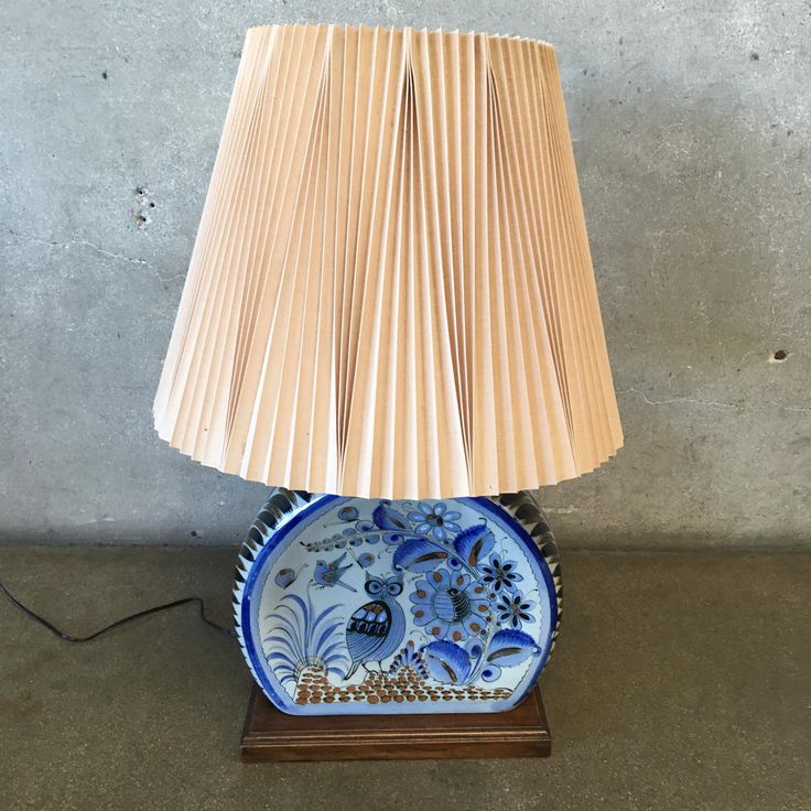 a blue and white lamp sitting on top of a wooden table next to a wall