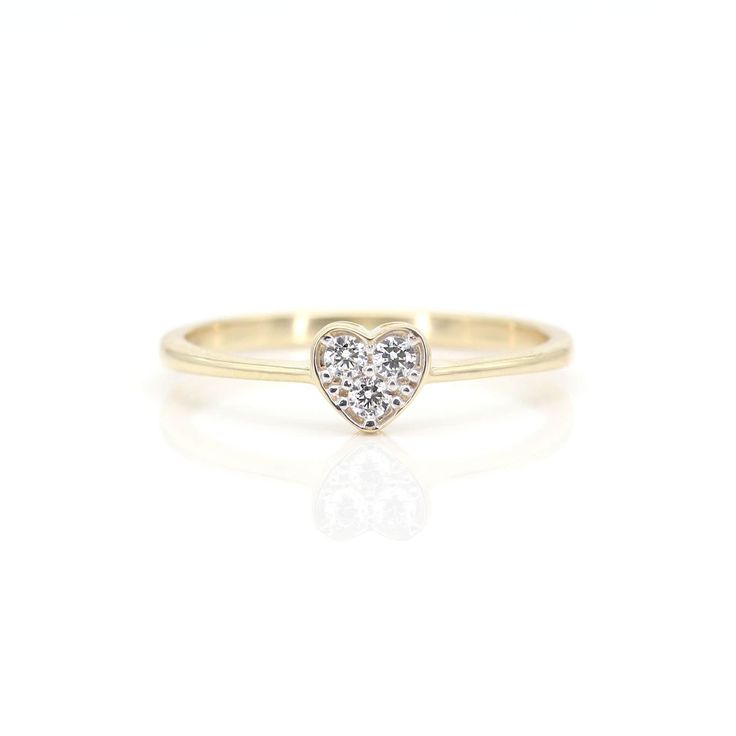 a yellow gold ring with a heart shaped diamond in the center, on a white background