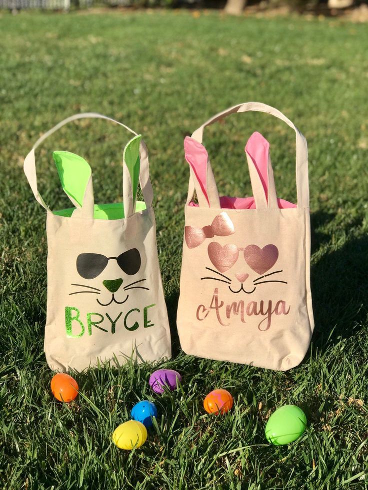 two bags with bunny ears on them sitting in the grass next to some easter eggs