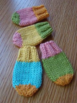 three knitted mittens sitting on top of a wooden table