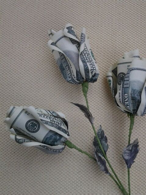 three roses made out of money sitting on top of a table