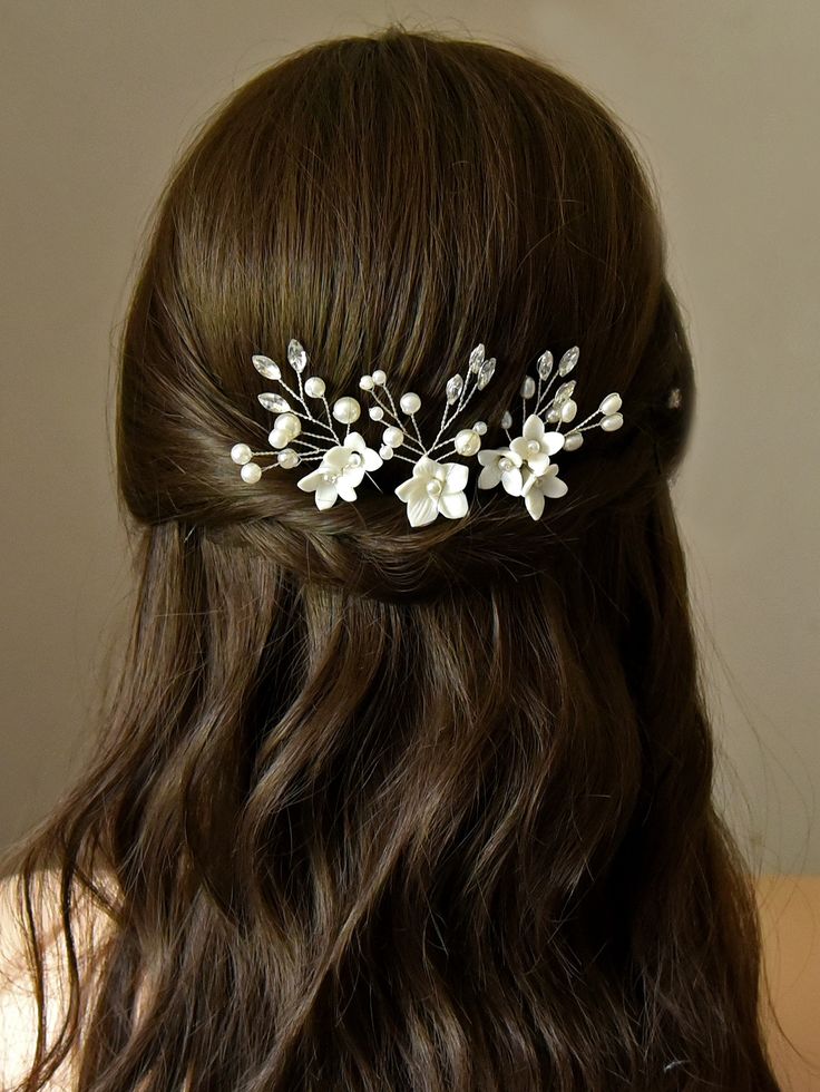 a woman with long brown hair wearing a white flower and leaf bridal headpiece