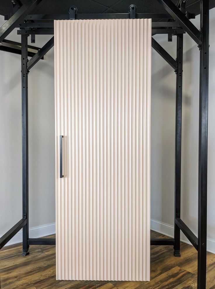 a tall white door sitting in the middle of a room next to a wooden floor