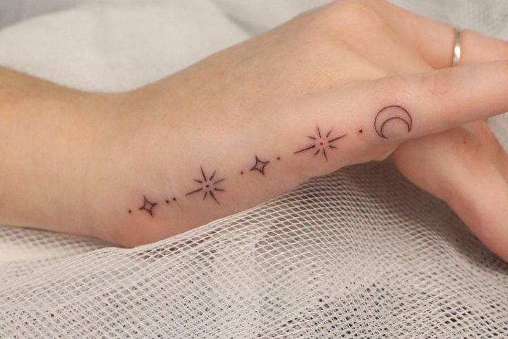 a woman's hand with stars and moon tattoos on it