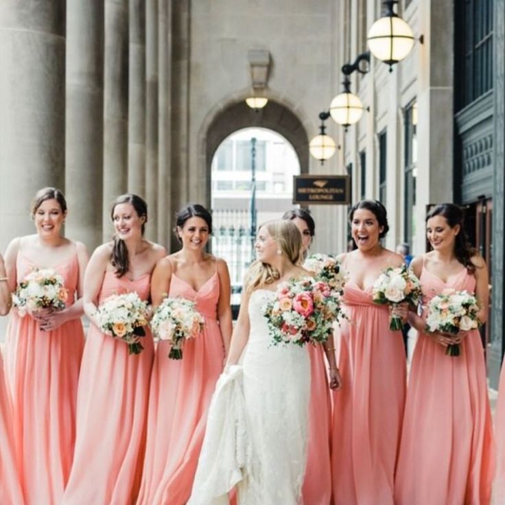 a group of women standing next to each other holding bouquets in their hands and smiling at the camera