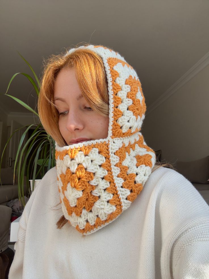 a woman wearing an orange and white crocheted cowl with a hood on her head