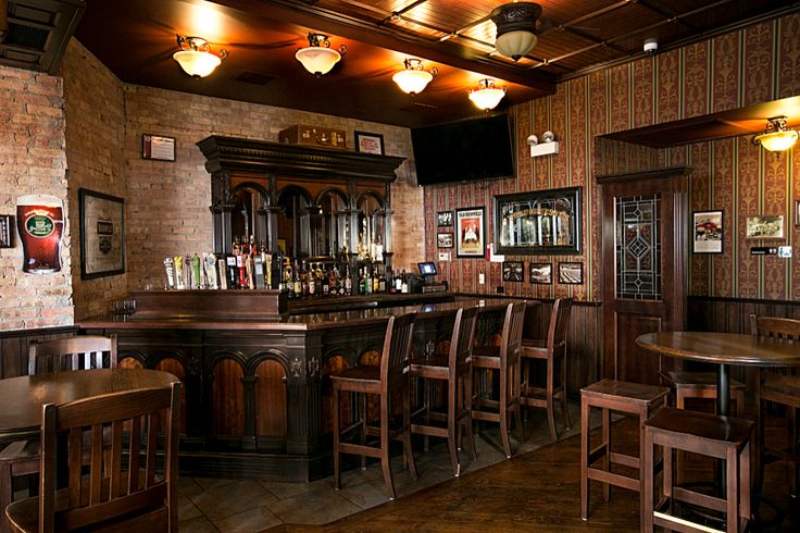 a bar with several wooden chairs and tables in front of brick wallpapered walls