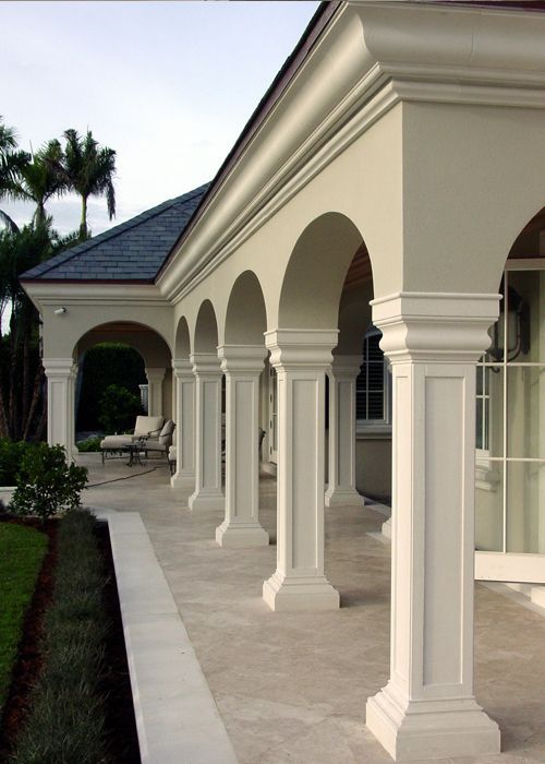 a row of white pillars sitting next to a lush green field