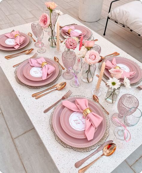 the table is set with pink plates and silverware