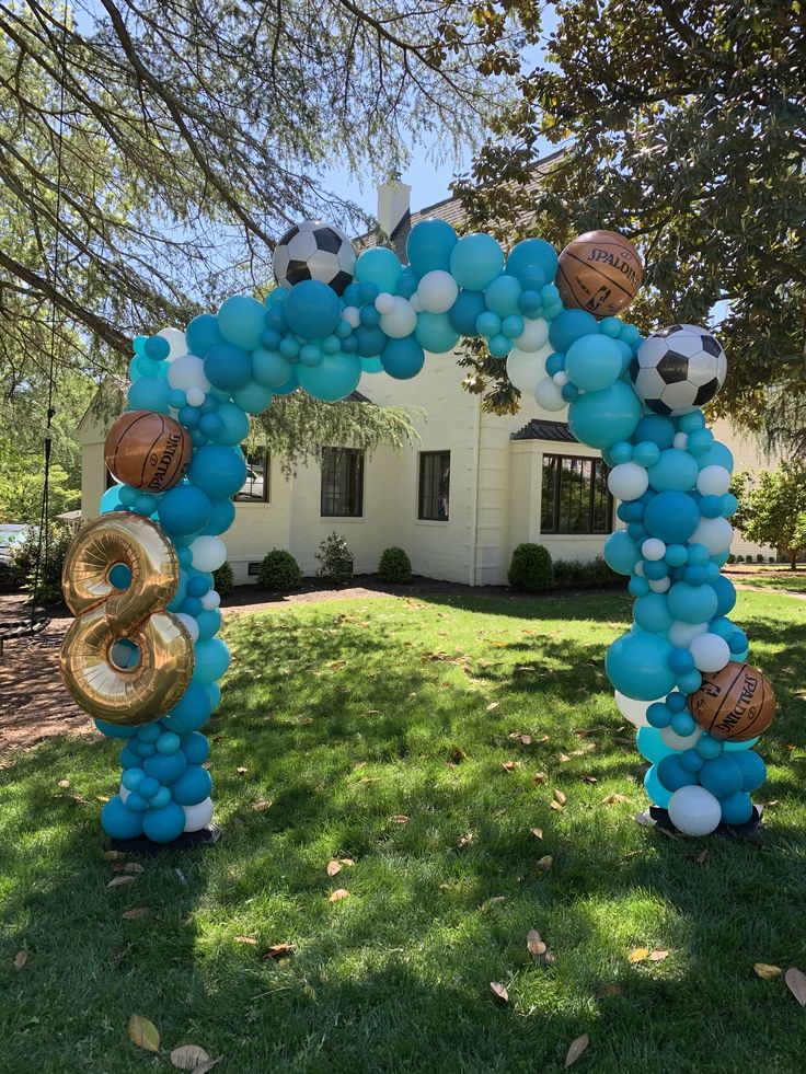 a balloon arch with soccer balls and basketballs on it in front of a house