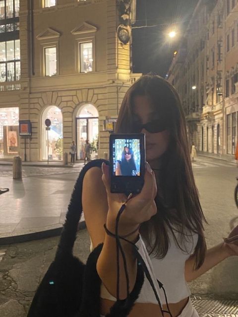 a woman taking a selfie with her cell phone in front of a city street