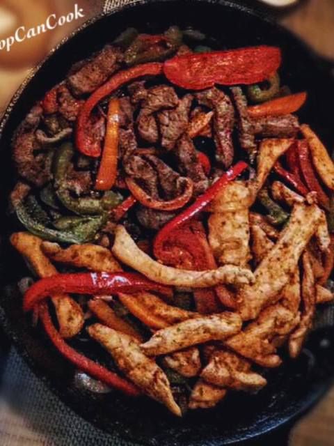 a skillet filled with meat and vegetables on top of a table